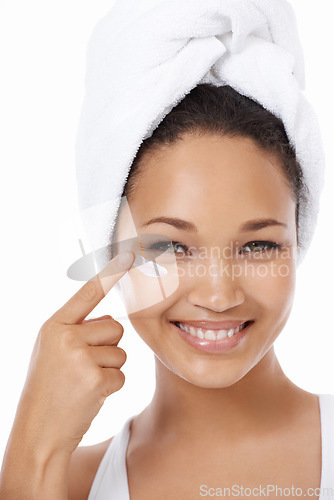 Image of Happy woman, face and beauty cream, skincare and cosmetics on a white background. Portrait of an African model or person smile and apply moisturizer, lotion or eye product for dermatology in studio