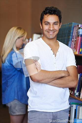 Image of Portrait, arms crossed or happy man in a library for knowledge or development for future growth. Scholarship, education or male student with smile or pride for studying or learning in college campus