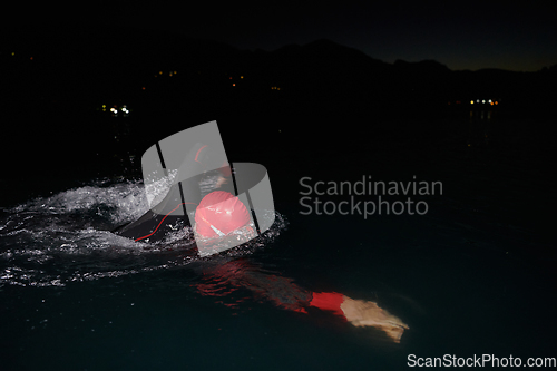 Image of A determined professional triathlete undergoes rigorous night time training in cold waters, showcasing dedication and resilience in preparation for an upcoming triathlon swim competition