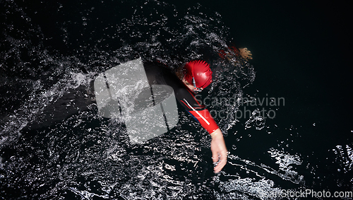 Image of A determined professional triathlete undergoes rigorous night time training in cold waters, showcasing dedication and resilience in preparation for an upcoming triathlon swim competition