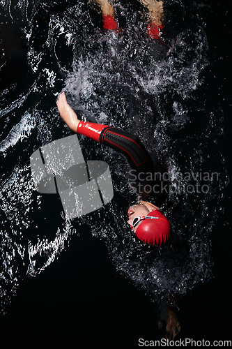 Image of A determined professional triathlete undergoes rigorous night time training in cold waters, showcasing dedication and resilience in preparation for an upcoming triathlon swim competition