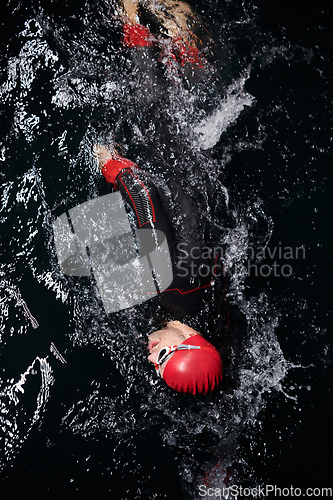 Image of A determined professional triathlete undergoes rigorous night time training in cold waters, showcasing dedication and resilience in preparation for an upcoming triathlon swim competition