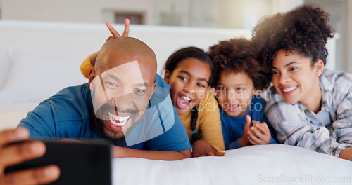 Image of Selfie, smile and children with parents in bed of modern home for bonding together with teddy bear. Happy, fun and young interracial man and woman laying for rest with kids in bedroom of family house