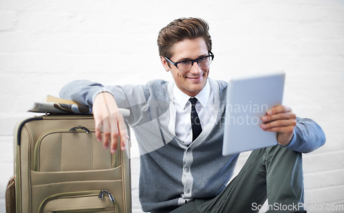 Image of Business man, reading or suitcase with tablet, floor and smile with app, flight or travel by wall background. Entrepreneur, person or touchscreen on social media, bag or check booking for immigration