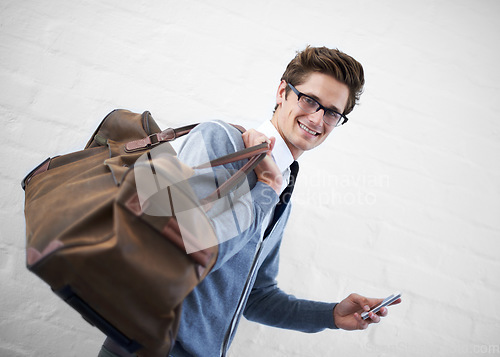 Image of Business man, bag and phone in portrait by wall background with click for booking app, schedule and travel. Entrepreneur, employee and smartphone for smile, reading and scroll on website for flight