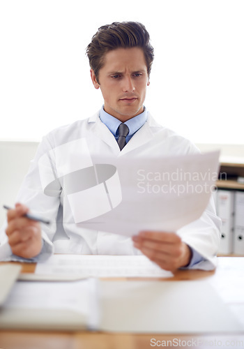 Image of Reading, document and portrait of man doctor in the office for consultation in a medical hospital. Serious, report and professional young male healthcare worker with paperwork for research in clinic.