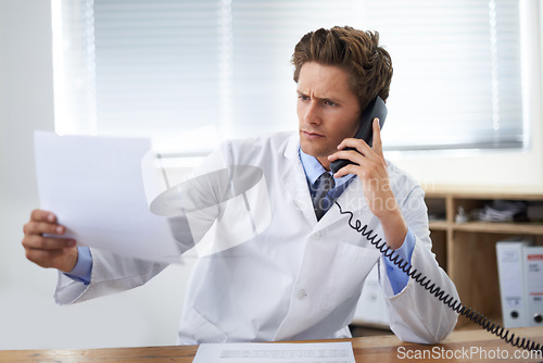 Image of Document, phone call and man doctor in his office for telehealth consultation at hospital. Confused, professional and young male healthcare worker on mobile discussion with landline in medical clinic