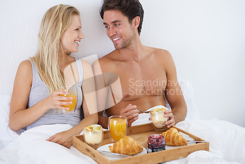 Image of Happy couple, food and breakfast in bed for morning, wakeup or early meal together in relax at home. Man and woman smile enjoying healthy snack, vitamin c juice or diet for love in bedroom at house