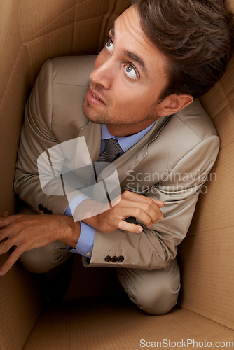 Image of Businessman, trapped and box at work with frustrated, scared and fear in office for career or startup. Entrepreneur, corporate and person isolated in cardboard at workplace with stress and anxiety