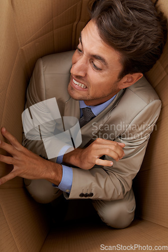 Image of Businessman, trapped and box at work with stress, scared and fear in office for career or startup. Entrepreneur, corporate and person isolated in cardboard at workplace with frustrated and anxiety