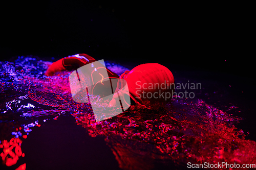 Image of Authentic triathlete swimmer having a break during hard training on night neon gel light