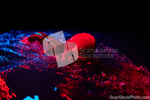 Image of Authentic triathlete swimmer having a break during hard training on night neon gel light