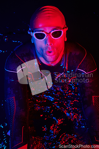 Image of authentic triathlete swimmer having a break during hard training on night neon gel light