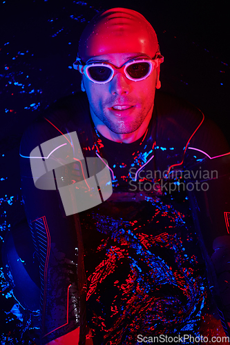 Image of authentic triathlete swimmer having a break during hard training on night neon gel light