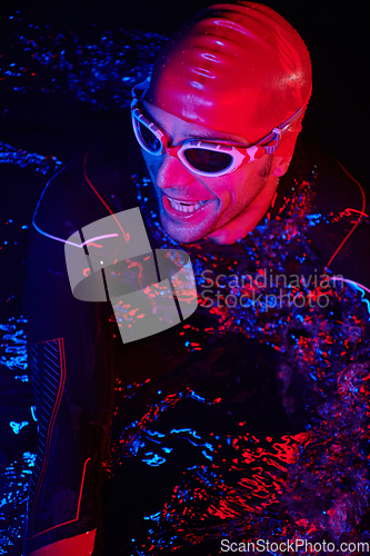 Image of authentic triathlete swimmer having a break during hard training on night neon gel light