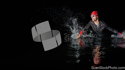 Image of A determined professional triathlete undergoes rigorous night time training in cold waters, showcasing dedication and resilience in preparation for an upcoming triathlon swim competition