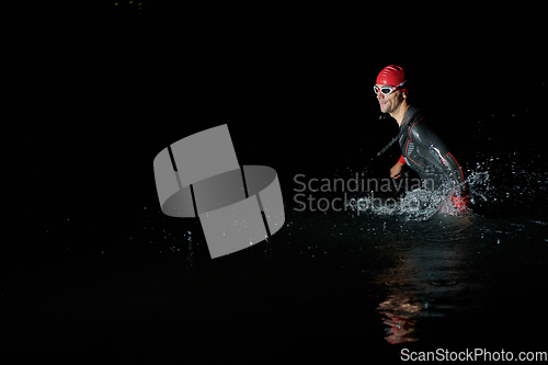 Image of A determined professional triathlete undergoes rigorous night time training in cold waters, showcasing dedication and resilience in preparation for an upcoming triathlon swim competition