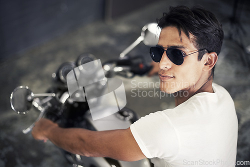 Image of Handsome man, portrait and sunglasses on motorcycle for cool transportation or small vehicle in garage. Face of young male person or biker smile for automobile or ownership on mechanical motorbike