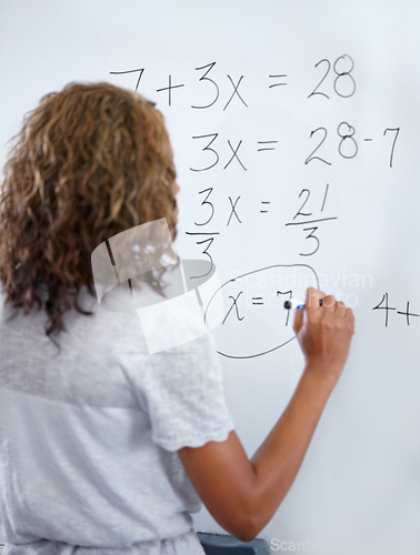 Image of Woman, teacher and writing on whiteboard for mathematics, numbers or equations in classroom. Rear view of female person, educator or lecturer with sum on board for learning or problem solving class