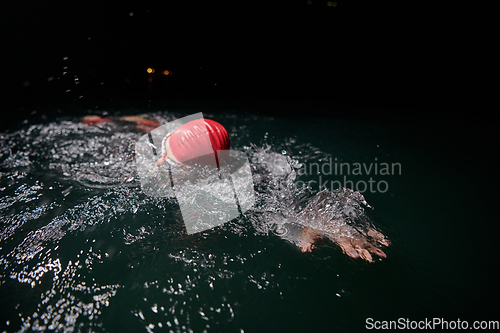 Image of A determined professional triathlete undergoes rigorous night time training in cold waters, showcasing dedication and resilience in preparation for an upcoming triathlon swim competition