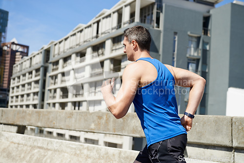 Image of Man, fitness and running on road in city for workout, exercise or outdoor cardio with buildings. Active male person, athlete or runner in training or practice for health and wellness in an urban town