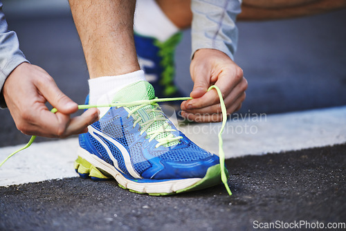 Image of Foot, runner and tying laces on street in outdoors, cardio and exercise or training for marathon. Person, athlete and ready for workout in closeup, sportswear and performance challenge on asphalt
