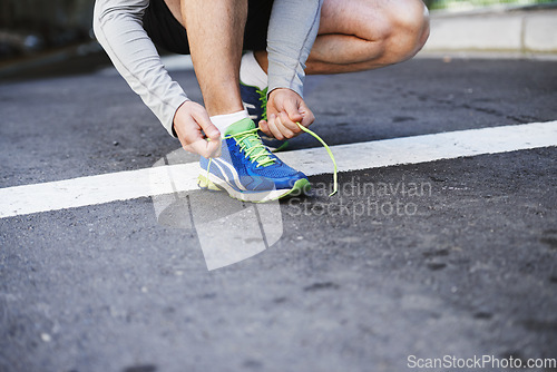 Image of Foot, runner and tying laces on road in outdoors, cardio and exercise or training for marathon. Person, athlete and ready for workout in closeup, sportswear and performance challenge on asphalt