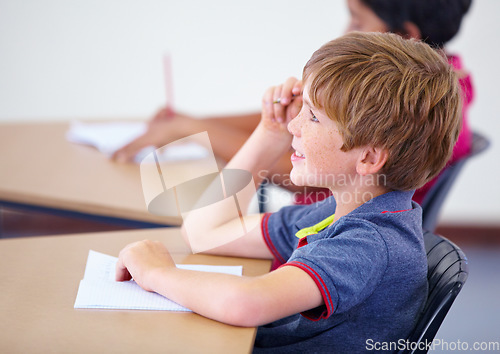 Image of Learning, happy child or student in classroom for knowledge, education or development for growth. School, smart boy or clever male kid with book, smile or pride for studying, focus or future at desk