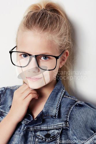 Image of Child, portrait and fashion glasses in studio, cool and confidence by white background. Female person, girl and casual clothing or style by backdrop, kid and denim jacket pride for eyesight test