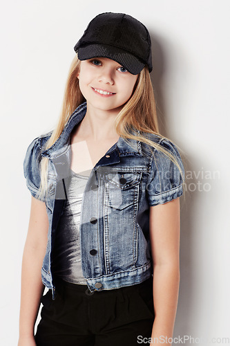 Image of Child, portrait and fashion in studio, cool and confidence by white background. Female person, girl and casual clothing or style by backdrop, kid and denim jacket pride or smiling for trendy cap