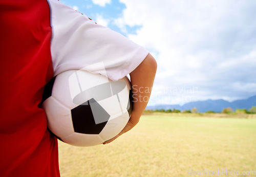 Image of Child, arm and soccer ball on green grass for sports, training or practice in cloudy blue sky. Closeup of football player, athlete or kid ready for kick off, game or match on outdoor field in nature