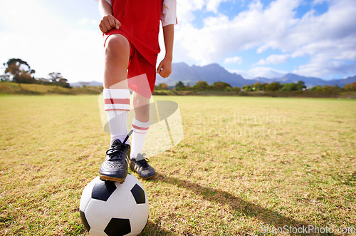 Image of Child, soccer ball and legs on green grass for sports, training or practice with clouds and blue sky. Closeup of football player with foot ready for kick off, game or match on outdoor field in nature