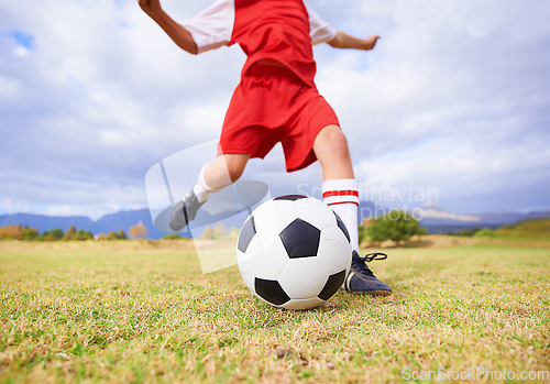 Image of Child, kicking and soccer ball on green grass for sports, training or practice with clouds and blue sky. Closeup of football player foot ready for kick off, game or match on outdoor field in nature