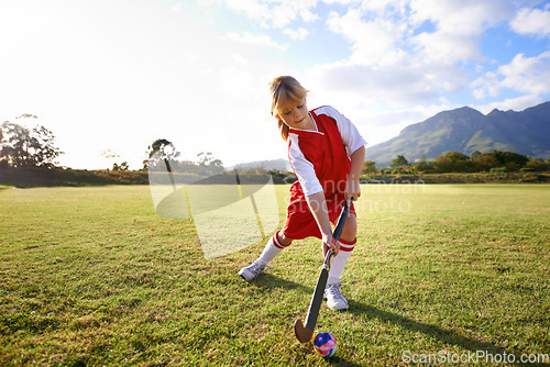 Image of Girl, green grass and playing hockey for sports, game or outdoor match in nature for practice. Female person, kid or playful child enjoying competition with ball on field for fitness or training