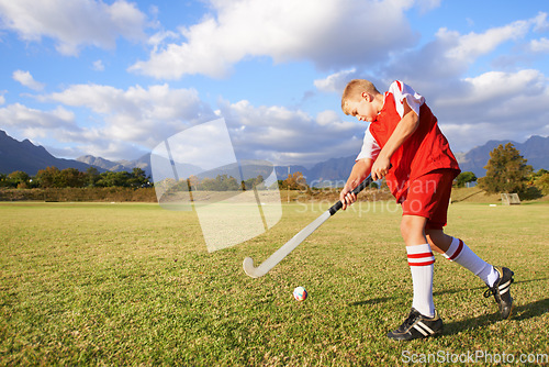 Image of Child, ball and hockey on field for sports, outdoor practice match or game in nature. Young kid or teen player enjoying day on green grass with stick for fitness, activity or training with blue sky