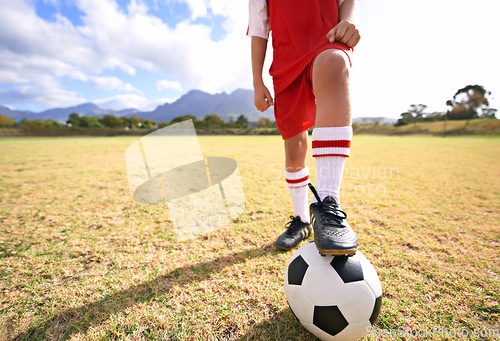 Image of Child, soccer ball and legs on green field for sports, training or practice with clouds and blue sky. Closeup of football player with foot ready for kick off, game or match on outdoor grass in nature