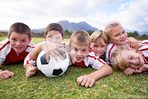 Image of Children, soccer ball and relax on green grass or field for outdoor match, game. or team sports. Group of kids, friends or football players smile lying together for competition on stadium in nature