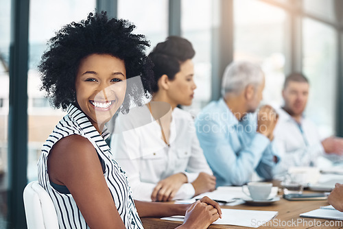 Image of Shes an invaluable member of the team. Portrait of a smiling businesswoman sitting in a boardroom with colleagues in the background.