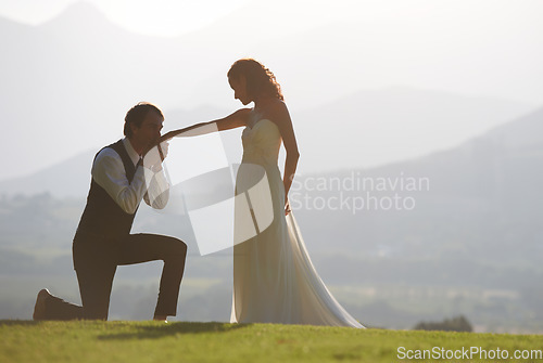 Image of Couple, garden or kiss on hand in wedding for outdoor celebration, care or ceremony event. One knee, romantic groom or proud bride in bridal garment for commitment, love or marriage in park for space