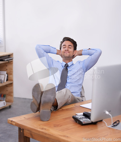 Image of Nap, relax or happy man in office on break for mental health, pride or wellness at his desk or workplace. Calm, business or employee sleeping with smile or hand behind his head stretching or resting