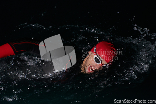 Image of A determined professional triathlete undergoes rigorous night time training in cold waters, showcasing dedication and resilience in preparation for an upcoming triathlon swim competition