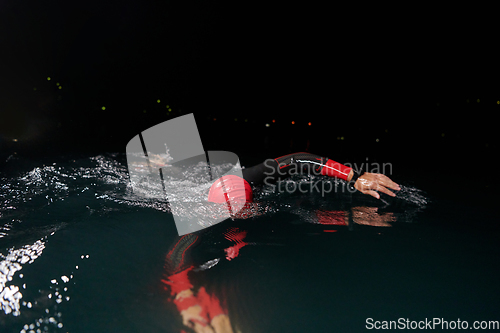 Image of A determined professional triathlete undergoes rigorous night time training in cold waters, showcasing dedication and resilience in preparation for an upcoming triathlon swim competition