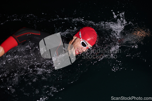 Image of A determined professional triathlete undergoes rigorous night time training in cold waters, showcasing dedication and resilience in preparation for an upcoming triathlon swim competition