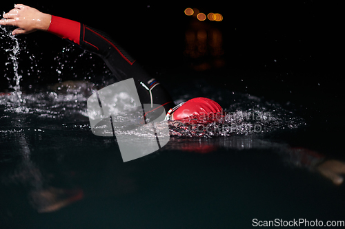 Image of A determined professional triathlete undergoes rigorous night time training in cold waters, showcasing dedication and resilience in preparation for an upcoming triathlon swim competition