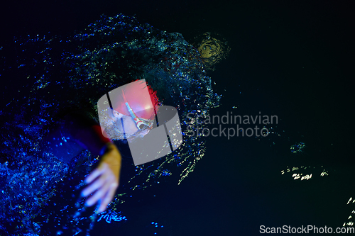 Image of Authentic triathlete swimmer having a break during hard training on night neon gel light