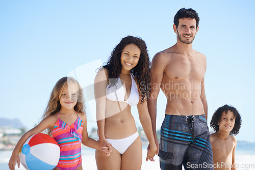 Image of Happy family, portrait and holding hands on beach for bonding, vacation or outdoor holiday weekend together. Father, mother and children smile with ball for summer break by the ocean coast in nature