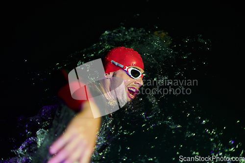 Image of Authentic triathlete swimmer having a break during hard training on night neon gel light