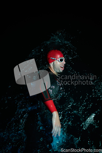 Image of Authentic triathlete swimmer having a break during hard training on night neon gel light