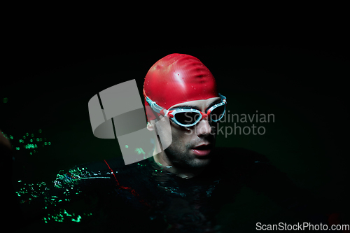 Image of Authentic triathlete swimmer having a break during hard training on night neon gel light