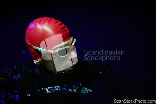 Image of Authentic triathlete swimmer having a break during hard training on night neon gel light